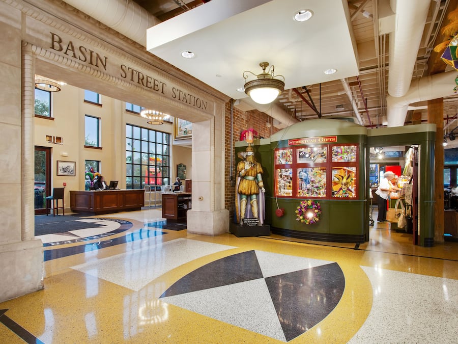 A lobby with a large sign reading "Basin Street Station" and a statue in the center.