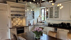 A kitchen with white cabinetry, a wooden dining table, and a unique chandelier. - Luxurious Holiday Home With Private Pool (Buzon)