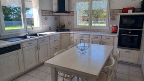 A kitchen with white cabinets, a black Bosch oven, a sink, and a window overlooking a garden. - Holiday Home in Normandy Near the Sea (Etretat)