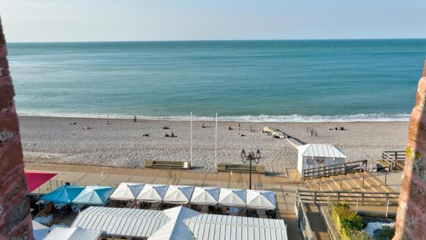 A beach with umbrellas and a building in the foreground. - Holiday Home in Normandy Near the Sea (Etretat)