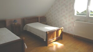A bedroom with a single bed, a nightstand, a chair, a window, and a radiator. - Holiday Home in Normandy Near the Sea (Etretat)
