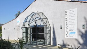 A spa building with a glass entrance and a sign listing services like massages and yoga. - Villa in Malaucene Near Mount Ventoux (Malaucene)