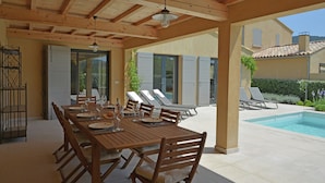 An outdoor dining area with a wooden table and chairs, a pool, and a covered patio. - Villa in Malaucene Near Mount Ventoux (Malaucene)
