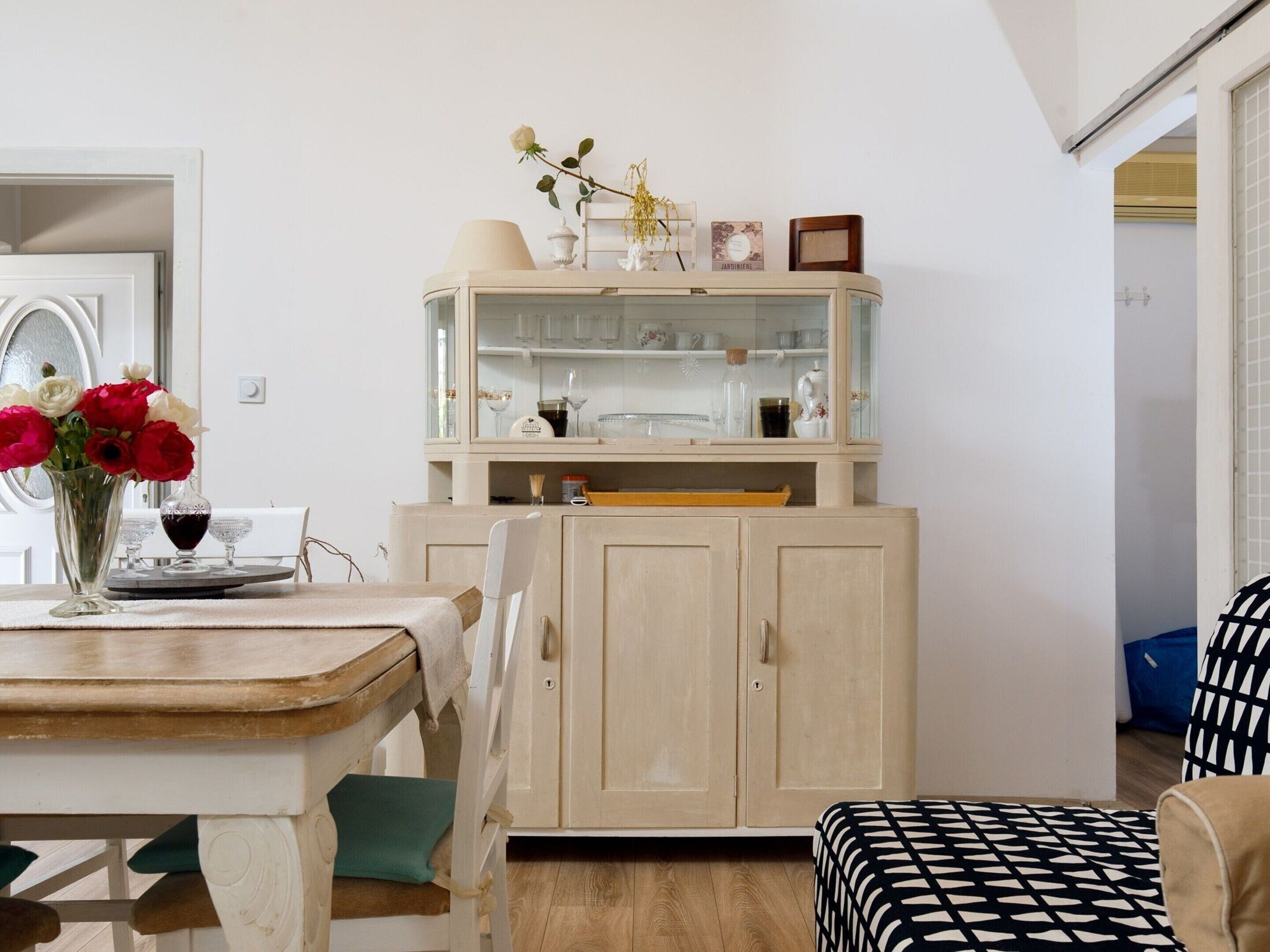 A room with a wooden dining table, a cabinet with glass doors, and a bench.