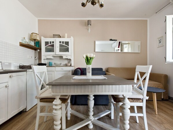 A modern kitchen with white cabinetry, a dining table with chairs, and a sofa in the living area.