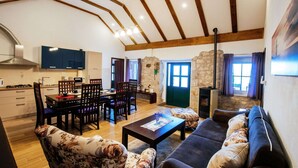 Un amplio espacio habitable con techo alto, vigas de madera, un juego de comedor, un sofá y una chimenea.