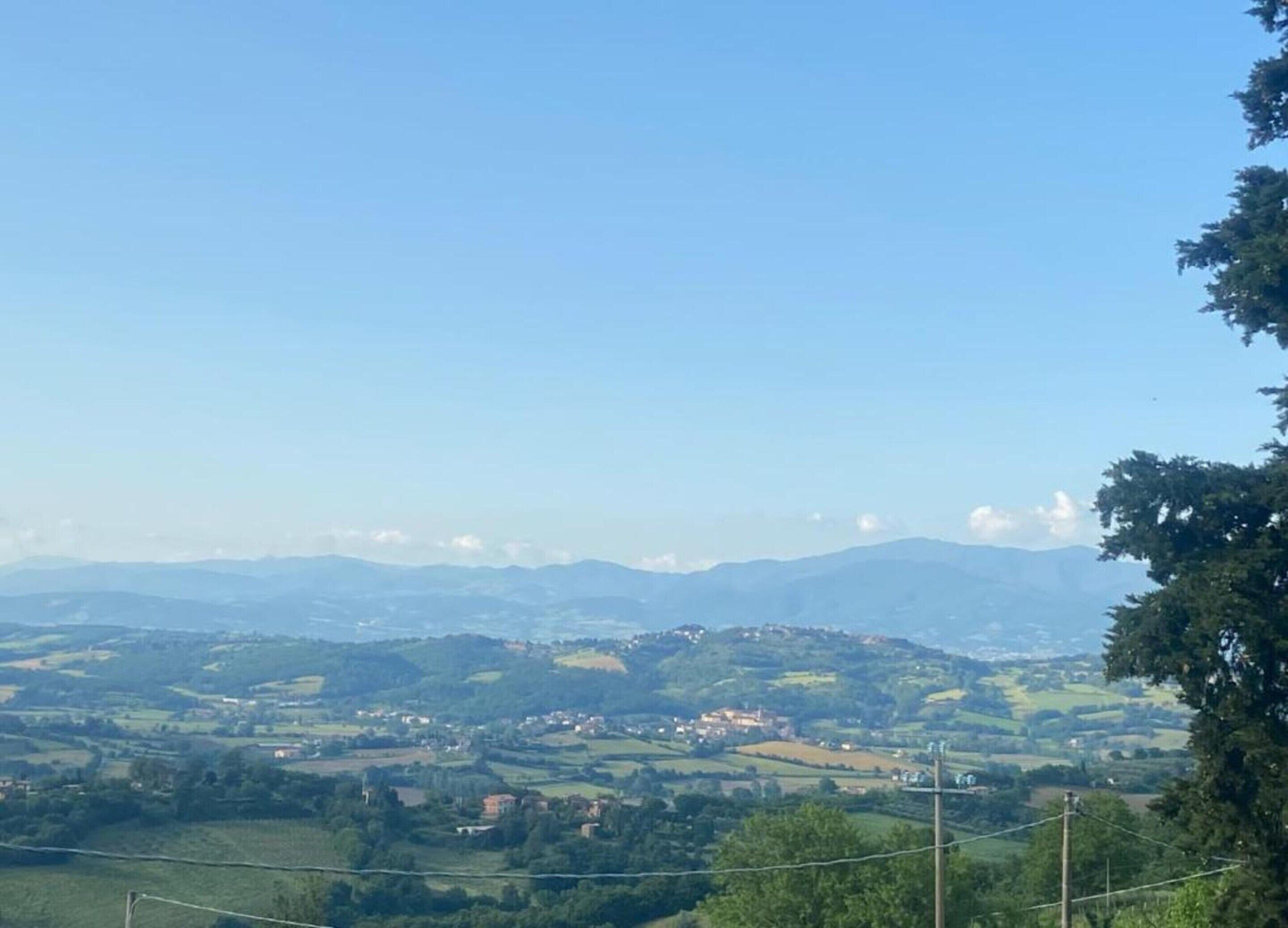 A panoramic view of a hilly landscape with scattered buildings, likely a rural area.