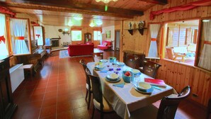 Comedor con una mesa dispuesta para cuatro personas, paredes de madera y un candelabro.