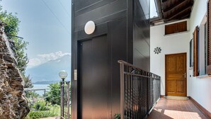 Un bâtiment moderne avec une façade noire, une porte en bois et une vue sur une montagne et un lac.