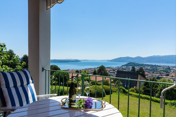 A balcony with a table set for two, overlooking a scenic view of a lake and cityscape.