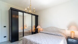 A bedroom with a large bed, a wardrobe with mirrors, two bedside lamps, and a chandelier. - Chalet in Verbania Near Lake Maggiore (Verbania)
