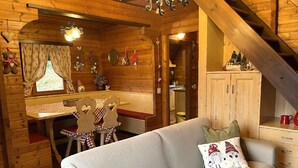 Ein gemütliches Blockhauss-Interieur mit einer Couch, einem Esstisch und Holzwänden.