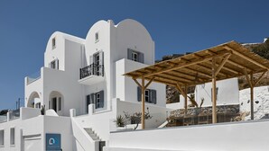 A white building with a wooden pergola, a staircase, and a sign reading "BlueWhite Villa". - Stunning BlueWhite Villa: Luxury Heated Infinity Pool Escape (Πύργος Καλλίστης)