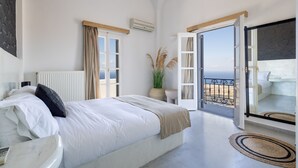 A bedroom with a bed, a bedside table, a potted plant, and a view of the sea through an open door. - Stunning BlueWhite Villa: Luxury Heated Infinity Pool Escape (Πύργος Καλλίστης)