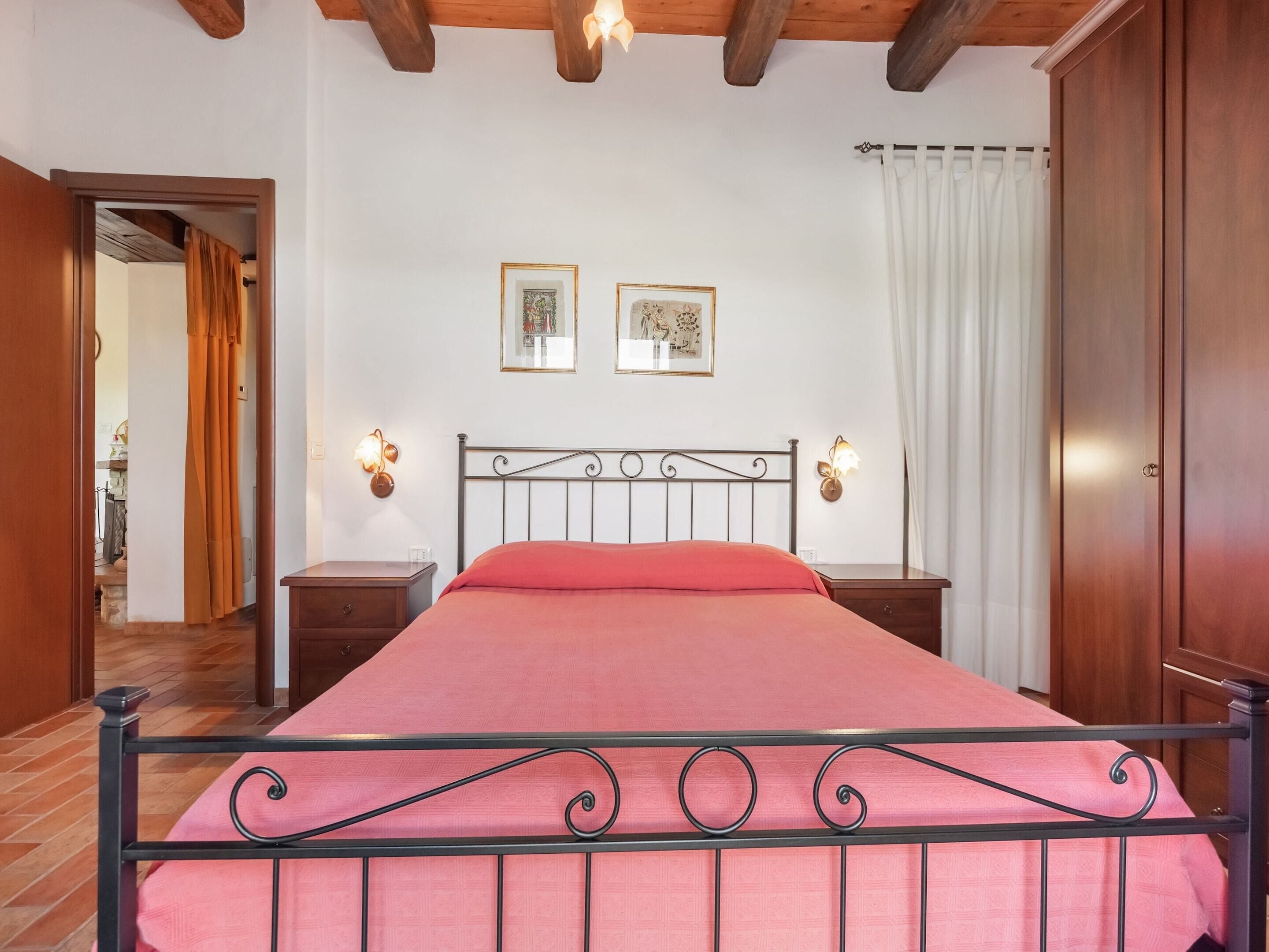 A bedroom with a bed, two bedside tables, a wooden wardrobe, and two wall-mounted light fixtures.