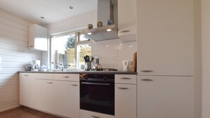 A modern kitchen with white cabinets, a built-in oven, and a window providing natural light.