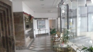 Eine großzügige Lobby mit einem Schachbrettmuster-Boden, einer Sitzecke mit Stühlen und Tischen sowie einem großen Gemälde an der Wand.