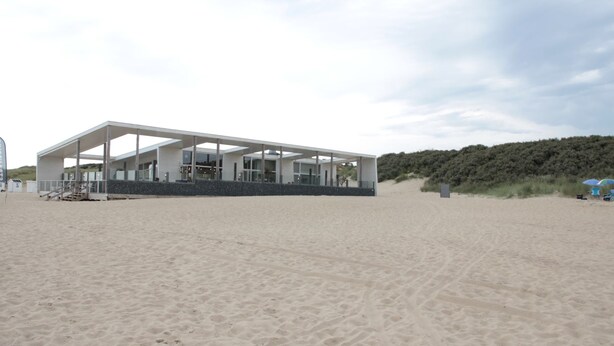 A modern beach house with a large open patio, situated on a sandy beach with a forested hill in the background. - Beautiful Villa Near the Beach of Cadzand (Cadzand-Bad)