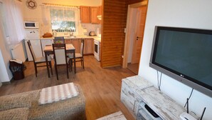 A compact living space with a kitchenette, a dining area, a sofa, and a TV.