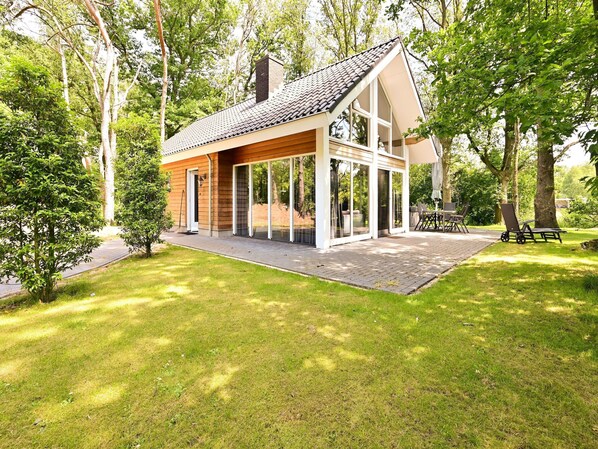A modern house with a large glass door, surrounded by a well-maintained lawn and trees. - Holiday Home in Reutum With Sauna (Reutum)