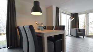 Ein moderner Essbereich mit einem Holztisch, grauen Polsterstühlen und einer Pendelleuchte.