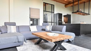 Ein modernes Wohnzimmer mit einer grauen Eckcouch, einem Holztisch und einem gemusterten Teppich.