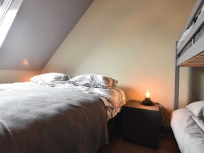 A bedroom with a bed, a bedside table with a lamp, and a bunk bed. - Grandeur Farmhouse in Dwingeloo at a National Park (Dwingeloo)
