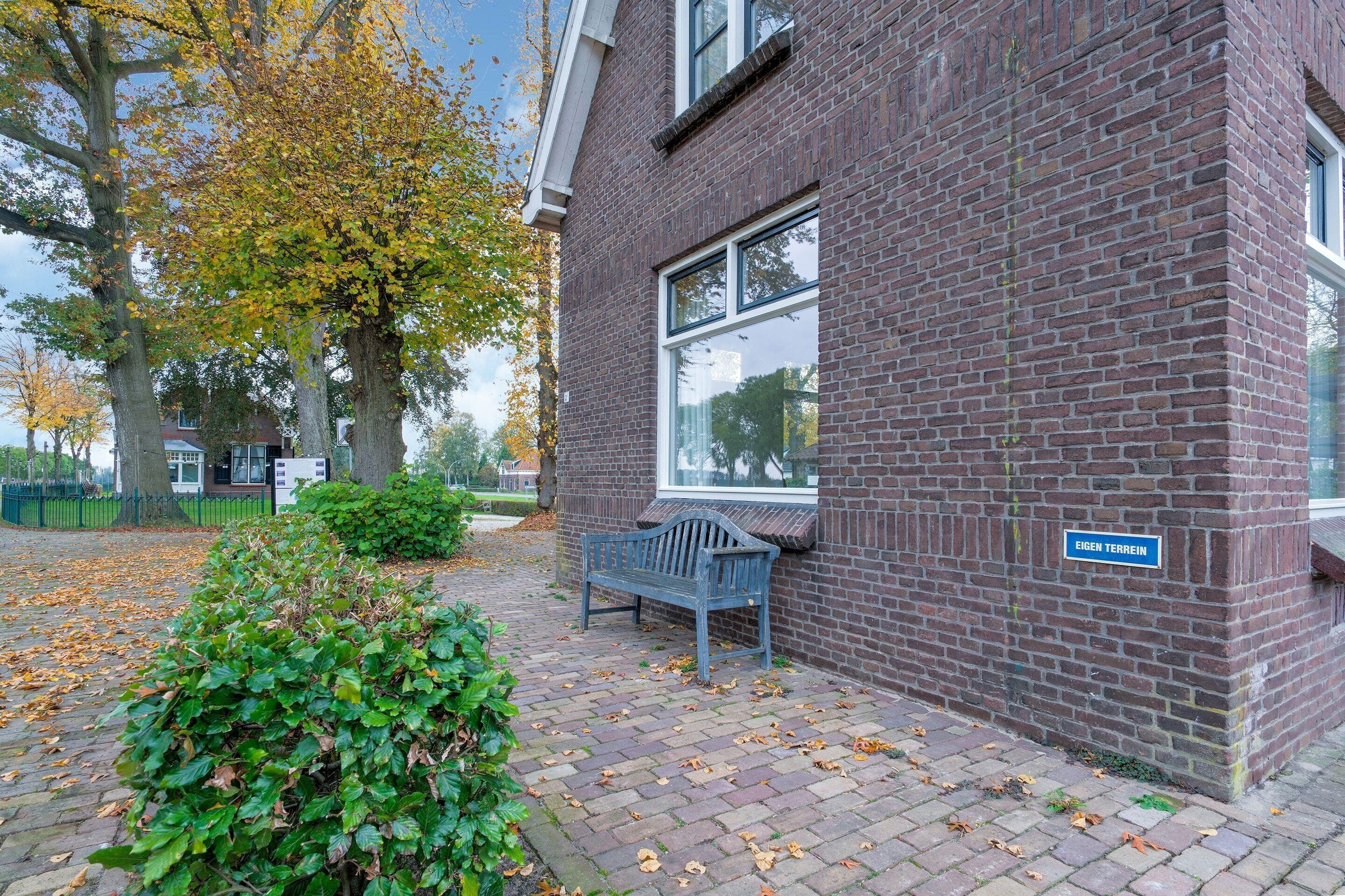 A brick building with a bench and a sign reading 'EIGEN TERREIN.'