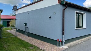 A building with a grey exterior, a green door, and a window with a white frame. - Hubsches Appartement in Kropelin mit Terrasse (Kroepelin)