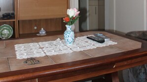 A living room with a television on a wooden cabinet, a vase with flowers on a table, and a remote control. - Hubsches Appartement in Kropelin mit Terrasse (Kroepelin)