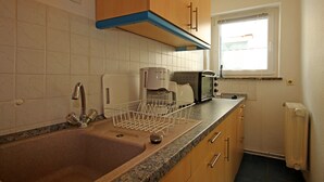 A kitchen with a sink, a coffee maker, a toaster, and a window. - Hubsches Appartement in Kropelin mit Terrasse (Kroepelin)