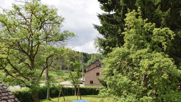 Ein Garten mit Schaukel, Tisch und Stühlen sowie einem Backsteinhaus im Hintergrund.