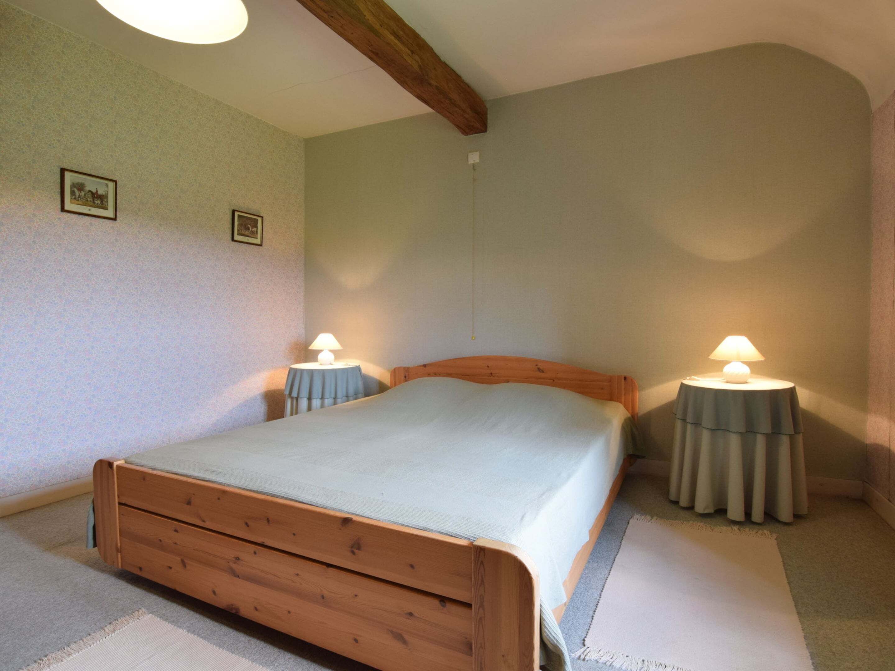 Een slaapkamer met een houten bed, twee nachtkastjes met lampen en een vloerbedekking.
