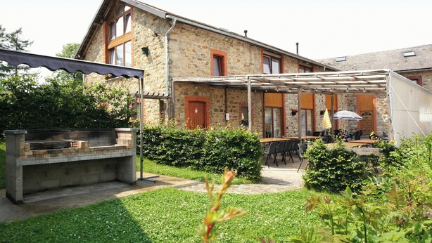 A stone building with a patio area, outdoor seating, and a grill.