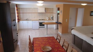 A compact kitchen with white cabinets, a dining table with chairs, and a sofa.