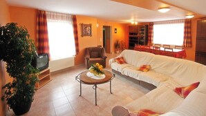 A living room with a sofa, a coffee table, a television, and a dining area with a table and chairs.