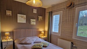 Un dormitorio con cama, dos mesitas de noche, una ventana y adornos en la pared.
