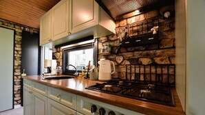 A kitchen with light blue cabinets, a stone wall, a wooden countertop, a gas stove, and a coffee maker. - Chalet With Balcony in Veluwe (Garderen)