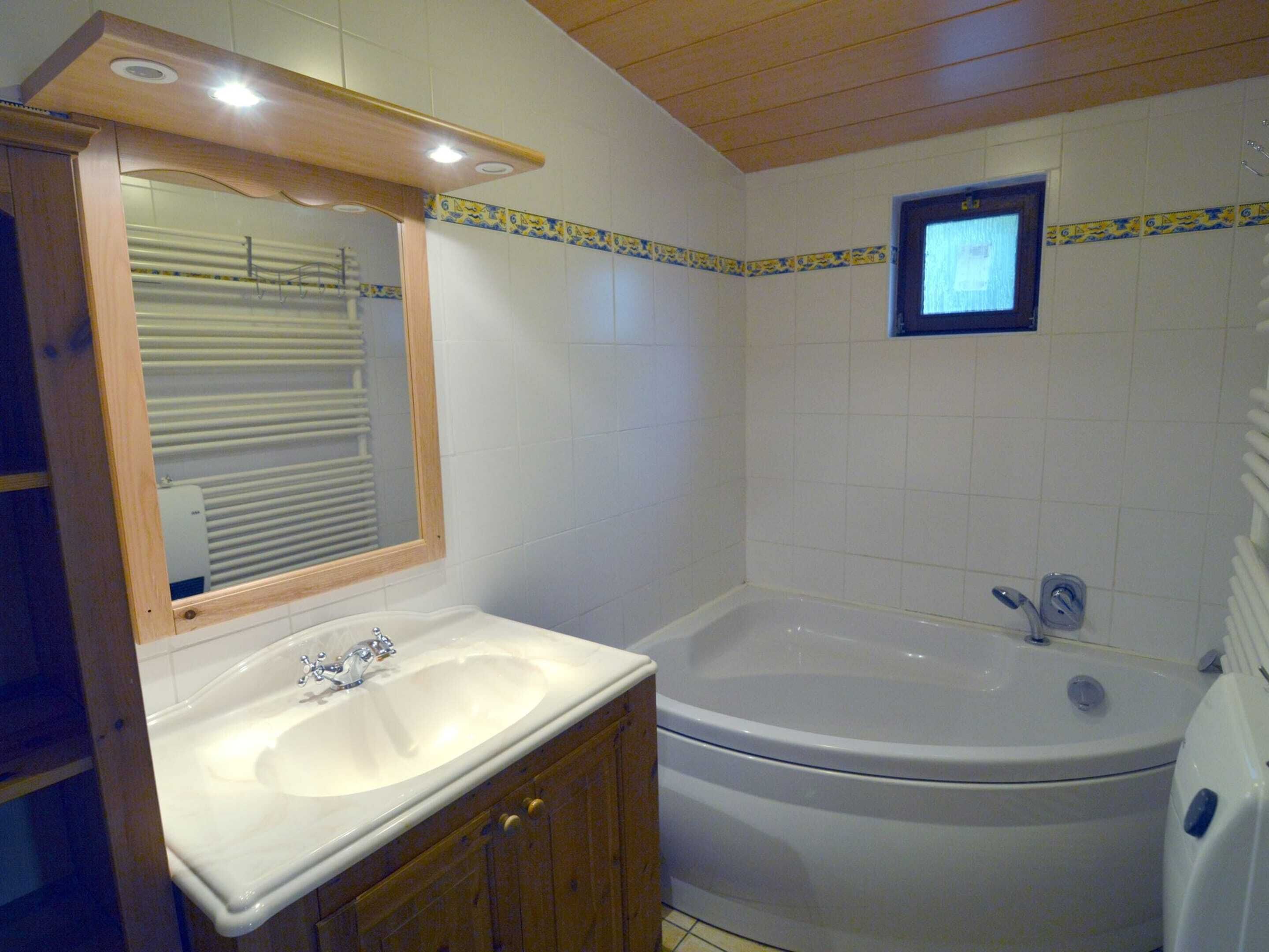 A bathroom with a sink, mirror, and bathtub.