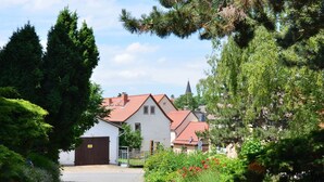 A cobblestone path leading to a row of houses with red-tiled roofs and a church steeple in the background. - Apartment in Harz Near Ski Slopes (Quedlinburg)