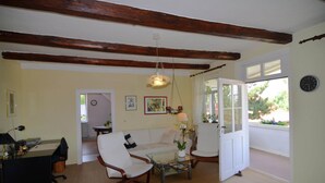 A spacious living room with a white sofa, two armchairs, a coffee table, and a desk with a lamp. A large window provides a view of the outdoors. - Apartment in Harz Near Ski Slopes (Quedlinburg)