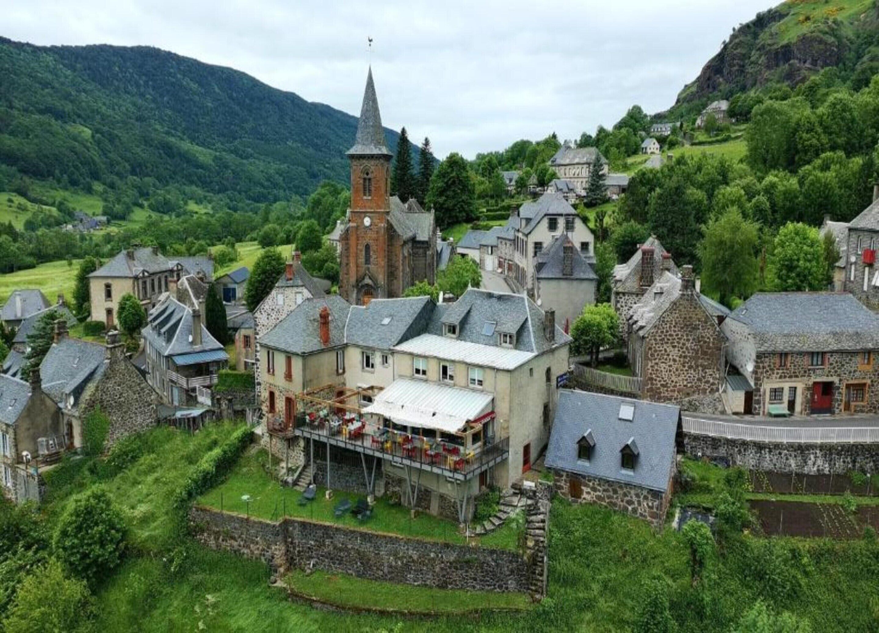 A historic village with stone buildings, a prominent church, and a central building with a balcony.