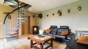 A living room with a staircase, a fireplace, a sofa, and deer antlers on the wall.