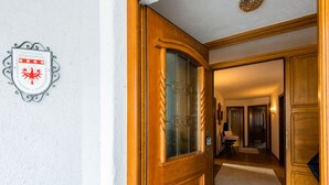 A wooden door with a glass panel, a coat of arms plaque on the wall, and a hallway leading to a room. - Beautiful Apartment in Langenfeld With Terrace (Laengenfeld)