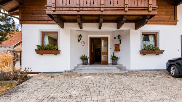 A traditional building with a wooden balcony, a stone-paved entrance, and potted plants on the facade. - Beautiful Apartment in Langenfeld With Terrace (Laengenfeld)