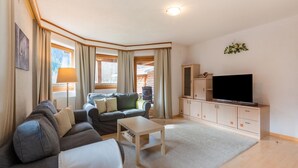 A living room with a sofa, a coffee table, a TV on a cabinet, and a window with curtains. - Beautiful Apartment in Langenfeld With Terrace (Laengenfeld)