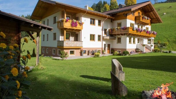 A two-story chalet with balconies, a well-maintained lawn, and a fire pit. - Apartment in Kaltenbach Near Ski Lift (Kaltenbach)