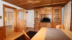 A wooden-paneled room with a bed, a television, and a dining area. - Apartment in Kaltenbach Near Ski Lift (Kaltenbach)