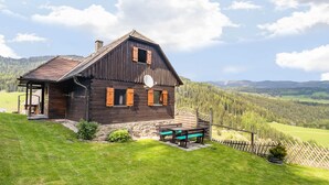 A rustic wooden house with a sloped roof, a satellite dish, and a wooden deck with benches. - Chalet in Kalchberg Near Klippitztorl Ski (Bad Sankt Leonhard im Lavanttal)