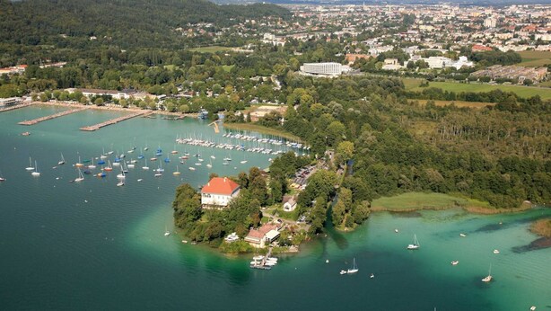 An aerial view of a coastal town with a marina, a large white building, and surrounding greenery. - Chalet in Kalchberg Near Klippitztorl Ski (Bad Sankt Leonhard im Lavanttal)